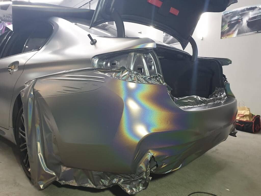 Lámina de vinilo camaleón colocada sobre el lateral trasero de un coche durante la instalación en el taller de XWrap en Valencia