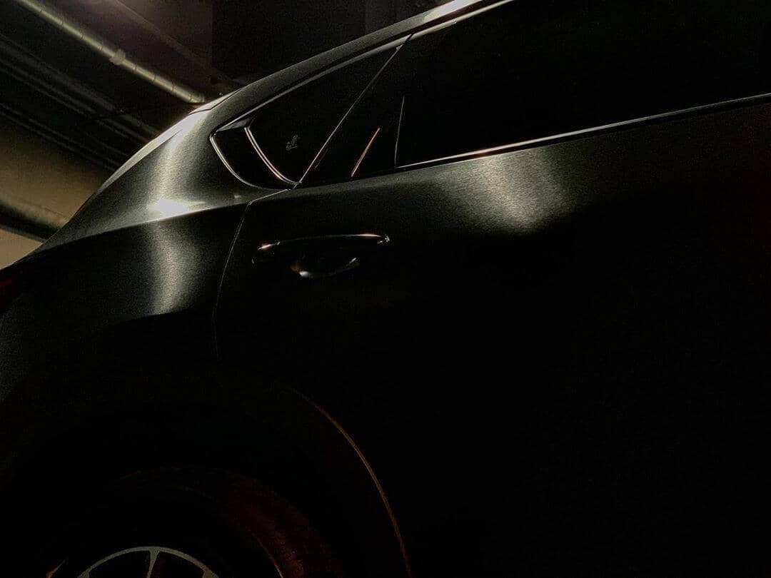 Puerta, ventanilla y aleta trasera de un coche revestido en negro satinado