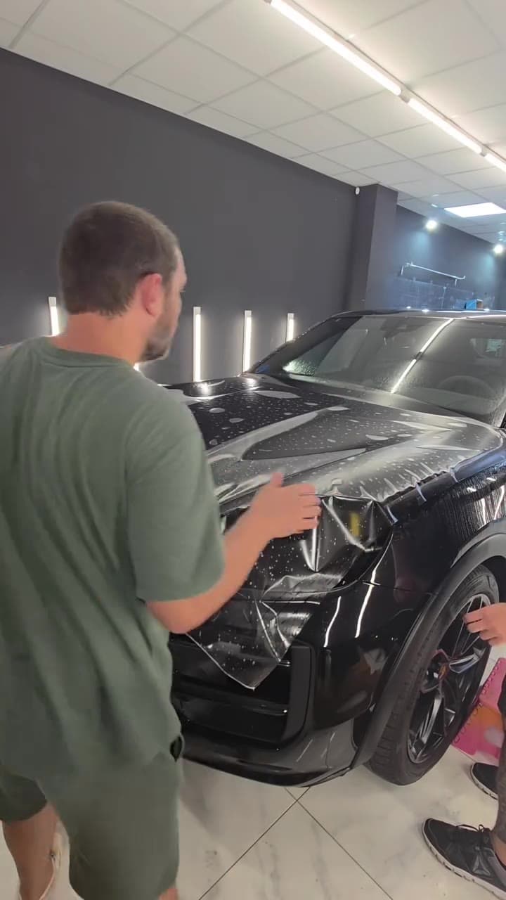 Montaje de PPF sobre el frontal de un Porsche Cayenne Coupé negro en el taller XWrap