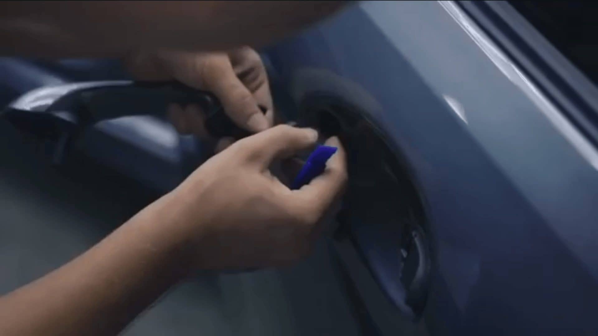 Remate de la lámina con espátula en la zona de la manilla de un coche azul en el taller de XWrap