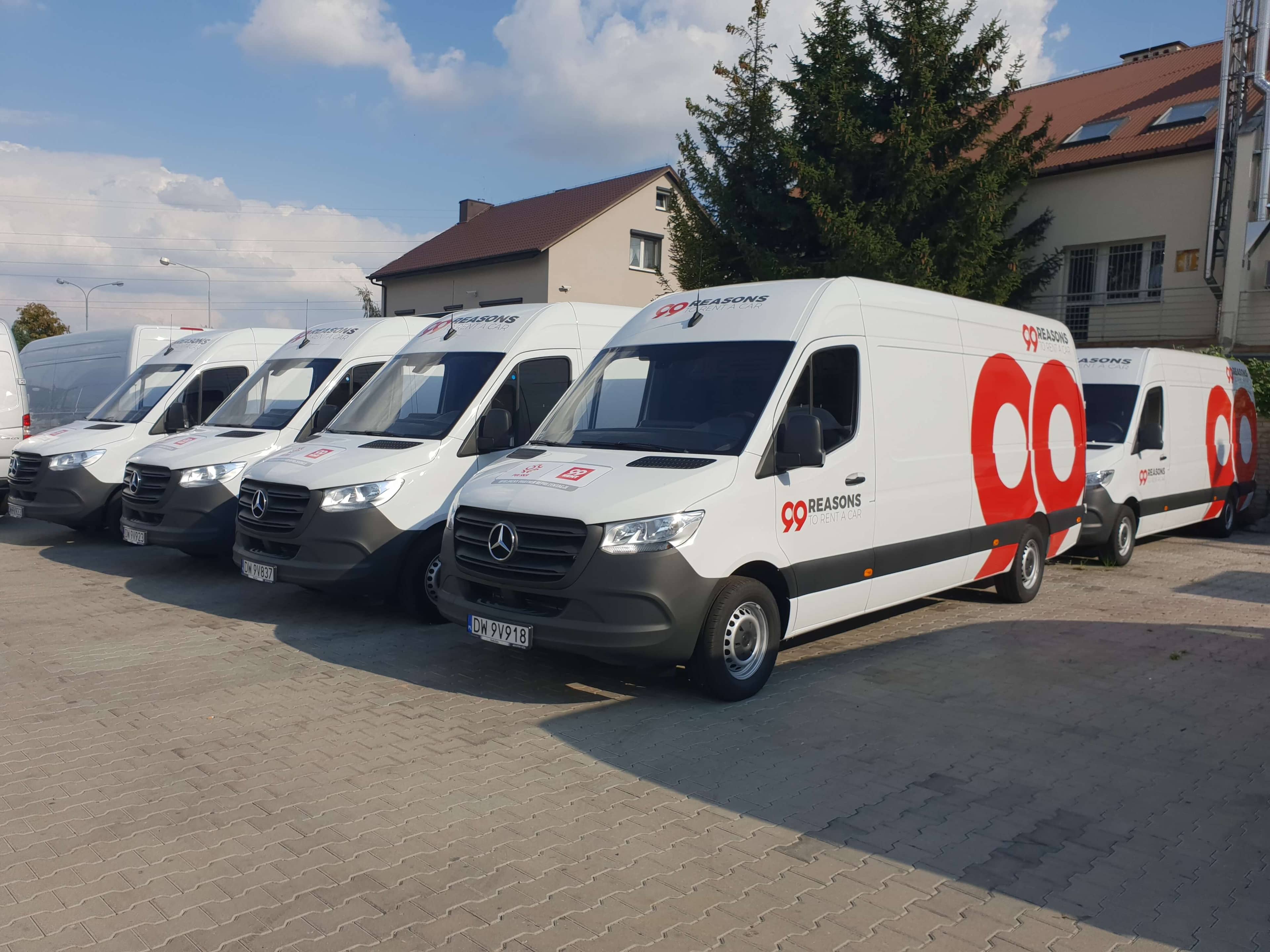 Flota de furgonetas Mercedes rotuladas con la imagen corporativa de una empresa, aparcadas en fila