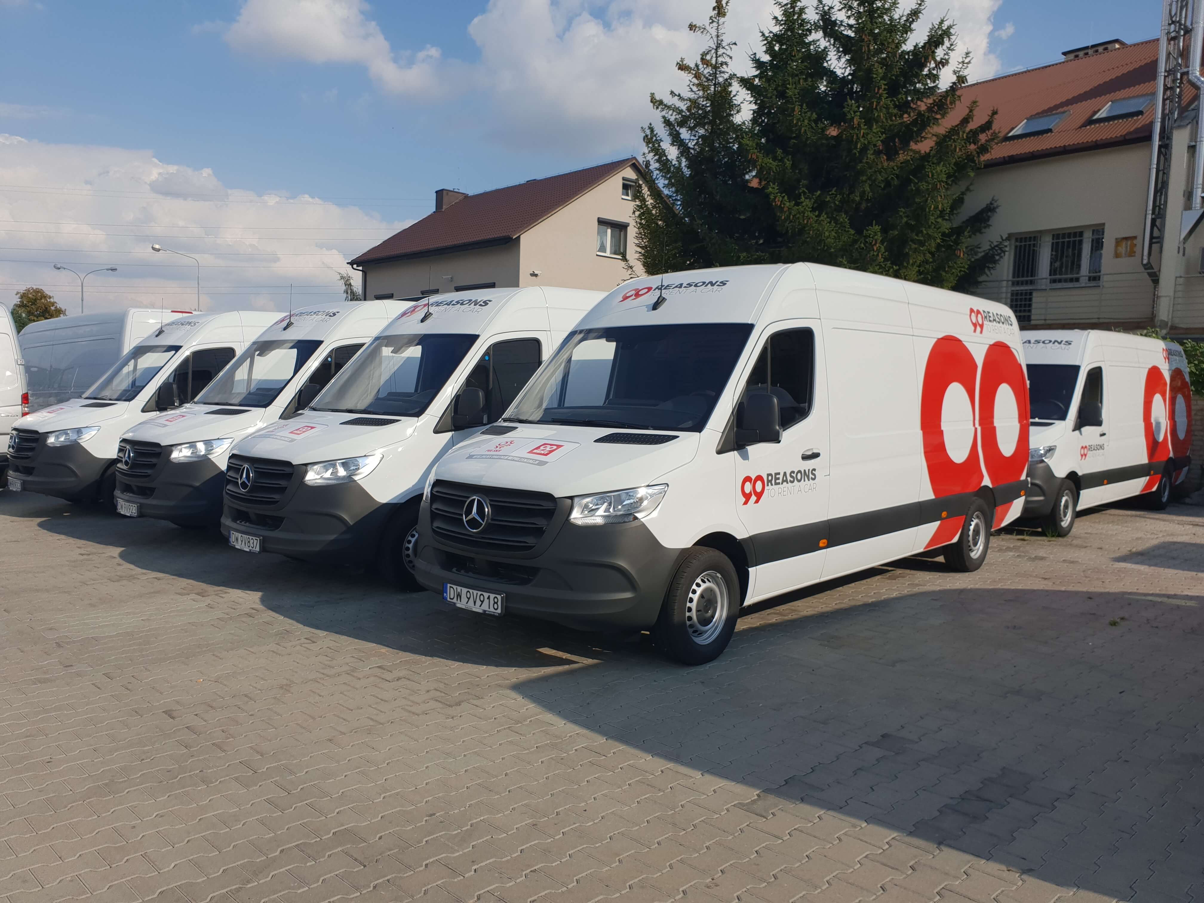 Flota de furgonetas Mercedes rotuladas con la imagen corporativa de una empresa, aparcadas en fila