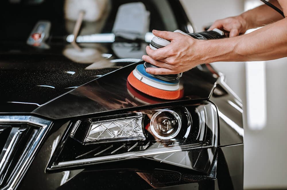 Clearcoat being corrected with a machine polisher on the front end of a car before PPF installation at the XWrap workshop in Valencia